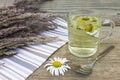 Clear transparent cup of camomile tea on vintage wooden background with dried herbs and daisy flowers. Royalty Free Stock Photo