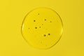 Clear transparent round liquid gel drop or smear isolated on yellow background. Top view. Virus protection or cosmetics concept.