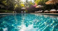 Sunlit Swimming Pool with Rippling Turquoise Water and Lounge Chairs in a Tropical Garden Setting blue Royalty Free Stock Photo