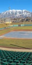 Clear Vertical Baseball field with green tiered seating against mountain and vibrant blue sky