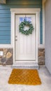 Clear Vertical Facade of a home with a simple leafy wreath hanging on the white front door