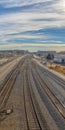 Clear Vertical Railroad tracks and roads with mountain and vibrant cloudy blue sky background