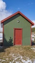 Clear Vertical Small wooden storage shed with a lamp on the green wall above the red door