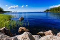 Clear water blue lake with stones and green forest on a sunny summer day in Finland. Royalty Free Stock Photo