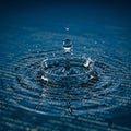 A clear water droplet creates a splash pattern as it falls onto a surface with visible Royalty Free Stock Photo