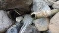 Clear water flows from a bamboo pipe among the rocks Royalty Free Stock Photo