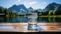 Clear water in a glass reflects the surrounding mountains and blue sky, symbolic of pure nature.