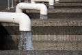 Clear water pours out with force from white curved pipes into concrete basins Royalty Free Stock Photo
