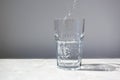 Clear water puring into glass on white wall background Royalty Free Stock Photo