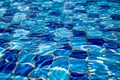 Clear water ripples over blue tiles, forming a mesmerizing abstract