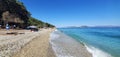 clear water on the sea pebble beach and a big mountain under the blue sky Royalty Free Stock Photo