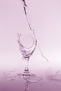 Clear water spill from a broken wine glass on colour background Royalty Free Stock Photo