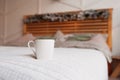 Clear white ceramic mug on cozy wooden bed in christmas decor with bedspread of pastel colors, pillows of powdery shades and