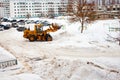 Clearing snow in Russia. Grader clears the way after a heavy snowfall. Tractor clears the road in the courtyard of a multi-storey