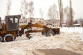 Clearing snow in Russia. Grader clears the way after a heavy snowfall. Tractor clears the road in the courtyard of a multi-storey