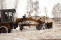 Clearing snow in Russia. Grader clears the way after a heavy snowfall. Tractor clears the road in the courtyard of a multi-storey