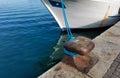 Cleat with blue hawser on the blue sea and white boat