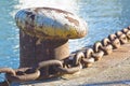 Cleat for mooring boats on concrete platform against a water background with rusty metal chain Royalty Free Stock Photo