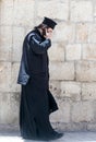 The clergyman stands and talks on his mobile phone in the old city of Jerusalem, Israel.