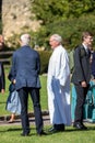 Clergyman in white cassock talking to parishioners after Sunday service outside Sherborne Abbey in Sherborne, Dorset, UK