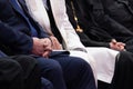 A clerk in costume, a Muslim mullah in white and a priest in a black are sitting next to each. Blurred. Shallow depth of field.
