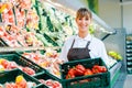 Clerk in a supermarket showing fresh vegetables Royalty Free Stock Photo
