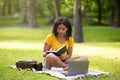 Clever black girl concentrated on her online studies with laptop at summer park Royalty Free Stock Photo