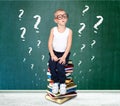 A clever boy with glasses sits on the books. A little scientist. Royalty Free Stock Photo