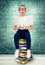 A clever boy with glasses sits and reads books. A little scientist. Royalty Free Stock Photo