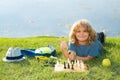 Clever concentrated and thinking child playing chess outdoor in park. Royalty Free Stock Photo