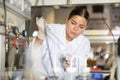 Clever female researcher in white coat mixing reagents in test tube with lab pipette while working in laboratory Royalty Free Stock Photo