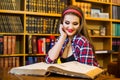 Clever female student girl sitting in library with books.