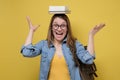 Clever female student holding book on head smiling and looking at camera