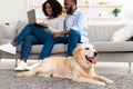 Black couple at home using pc laptop relaxing with dog Royalty Free Stock Photo