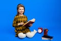 Clever little child using magnifying glass to read book during studies