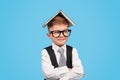 Smart schoolboy with book on head