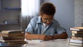 Clever male pupil doing math homework, solving equation in notebook, knowledge