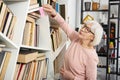 Clever mature woman sticking on shelf hieroglyph