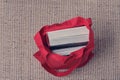 Clever thick books with a red spine in a hard dark cover in an open red fabric bag.