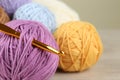 Clews of colorful knitting threads and crochet hook on wooden table, closeup Royalty Free Stock Photo