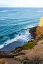 Clff side view of pacific ocean wavy shore and rocks, from sandy iceplant edged path Royalty Free Stock Photo