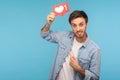 Click Like! Portrait of cheerful handsome blogger man in denim shirt pointing at social media heart Like button