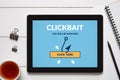 Clickbait concept on tablet screen with office objects