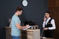 Client registering at desk while receptionist talking on phone