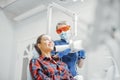 Client smiling while dentist in blue uniform holding x-ray.