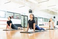 Clients Performing Upward Facing Dog Position In Gym