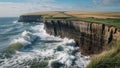 Cliff base catching waves while wind bends grass on headland far above Royalty Free Stock Photo