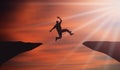Cliff Jumping Sunset. Young happy man Jump Over Mountain Cliffs in front Of Orange sky and Sun shine Rays. Overcoming difficulties Royalty Free Stock Photo