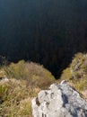 A cliff on a mountain with an evergreen forest in a shady valley Royalty Free Stock Photo