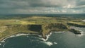 Cliff ocean Ireland coast aerial view: green grass meadows with little cottages in farmland